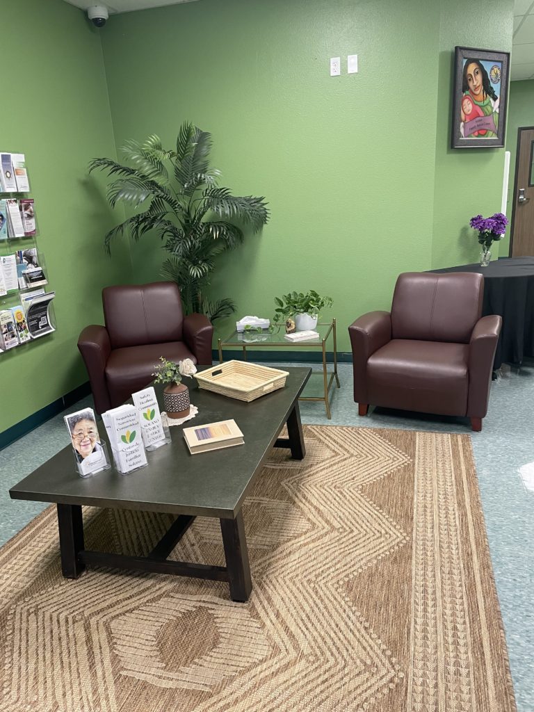 FJC lobby has green walls and two comfy brown armchairs, and a coffee table with brochures and plants