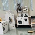The play kitchen includes sink, refrigerator and old-style stove with cooking tools in drawers.