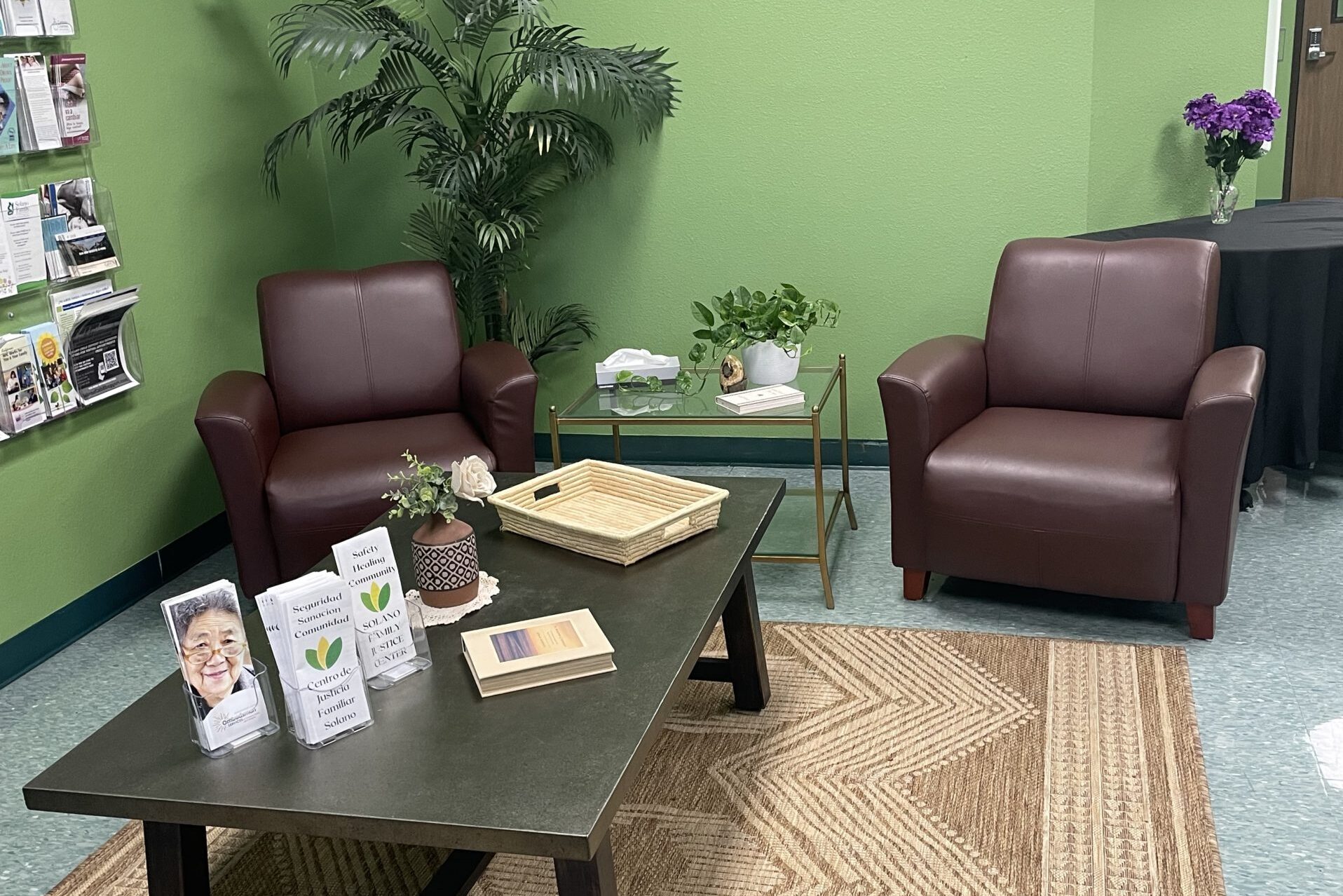 FJC lobby has green walls and two comfy brown armchairs, and a coffee table with brochures and plants